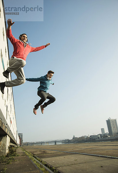 Junger Mann und Teenager springen in der Luft