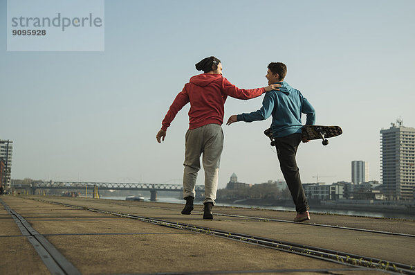Junger Mann und Teenager mit Skateboard