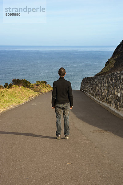 Portugal  Azoren  San Miguel  Mann auf der Straße mit Blick auf das Meer