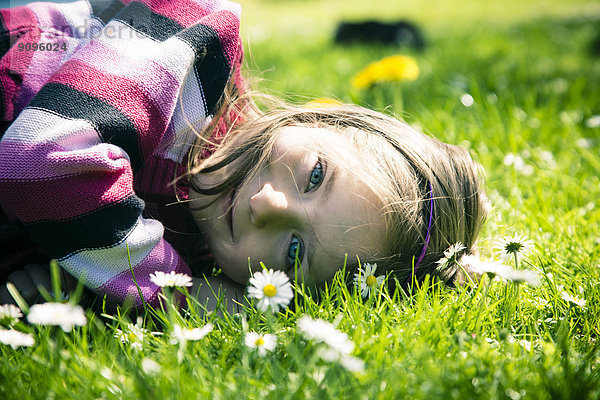 Porträt eines kleinen Mädchens auf der Wiese liegend