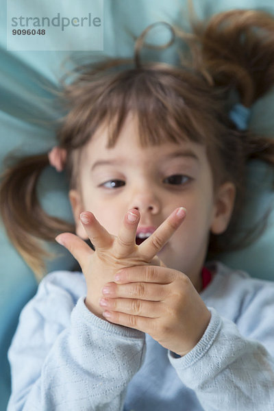 Porträt eines kleinen Mädchens auf Bohnensäckchen liegend  mit Fingern gezählt  erhöhte Ansicht