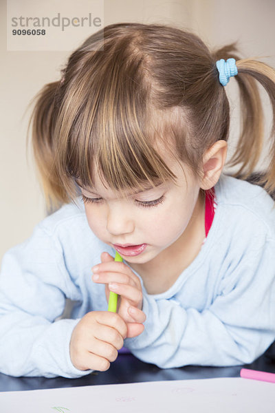Porträt eines kleinen Mädchens mit Wachsmalkreide beim Betrachten ihres Gemäldes