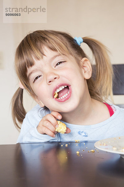 Porträt des kleinen Mädchens beim Kuchenessen mit offenem Mund