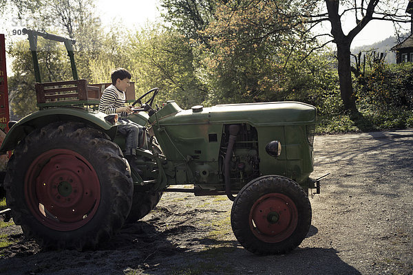 Germany  North Rhine-Westphalia  Detmold  Smiling child on tractor  playing to drive