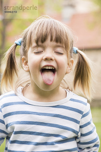 Porträt eines kleinen Mädchens mit geschlossenen Augen und ausgestreckter Zunge