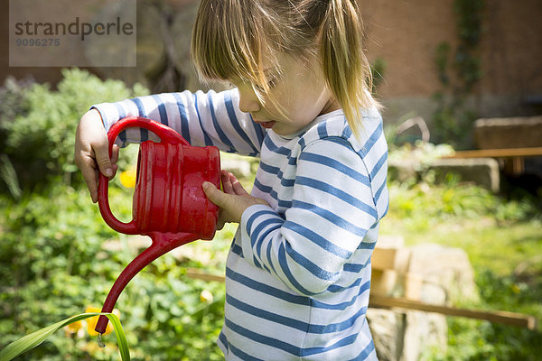 Kleines Mädchen gießt Pflanzen im Garten