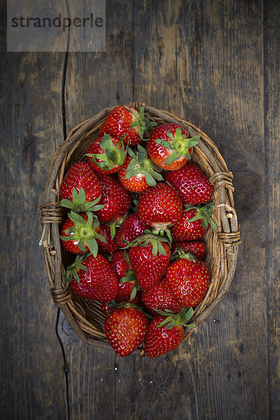 Korb mit Erdbeeren auf dunklem Holz  Blick von oben