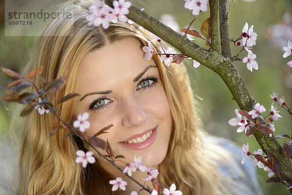 Junge Frau an blühendem Kirschbaum  Portrait