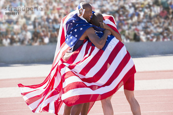 Leichtathleten mit amerikanischer Flagge auf der Rennstrecke