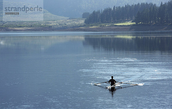 Mann mit Ruderschädel auf dem See