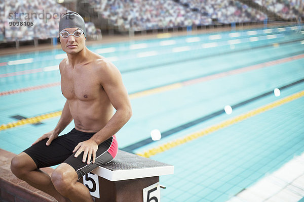 Schwimmer auf dem Startblock am Pool sitzend