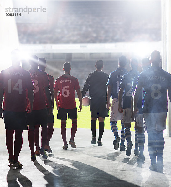 Silhouette der Fußballspieler  die zum Spielfeld gehen