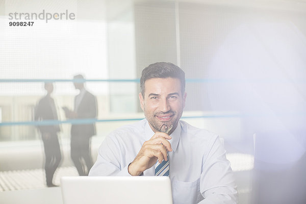 Portrait des selbstbewussten Geschäftsmannes am Laptop im Büro