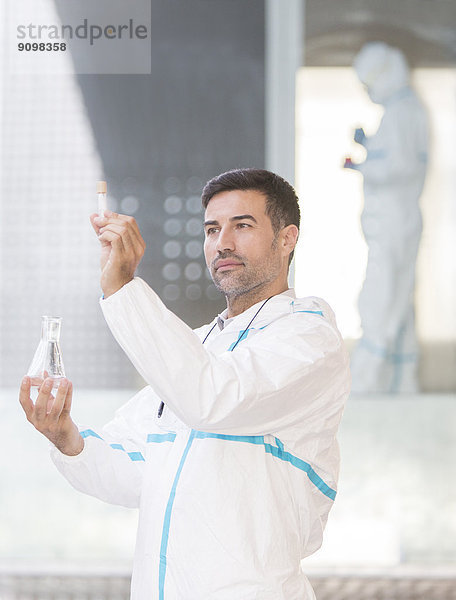 Wissenschaftler im Clean Suit untersucht Flüssigkeit im Reagenzglas