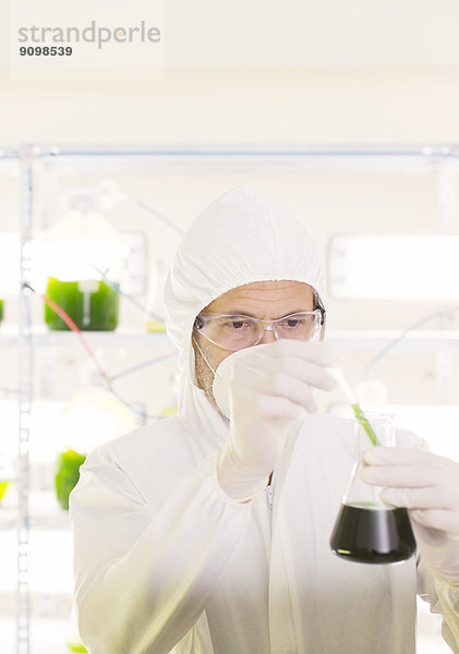 Wissenschaftler im sauberen Anzug mit Becherglas im Labor