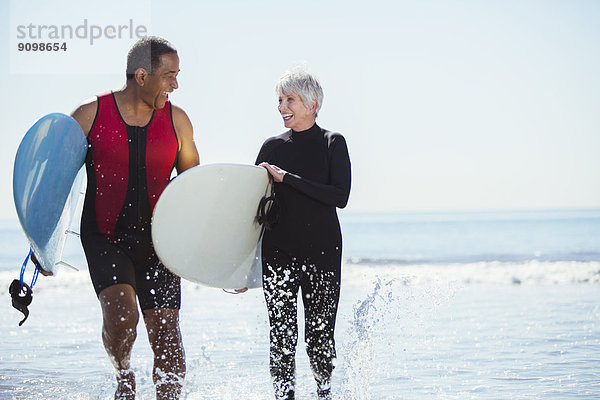 Seniorenpaar mit Surfbrettern am Strand
