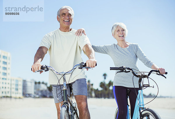 Seniorenpaar mit Fahrrädern am Strand