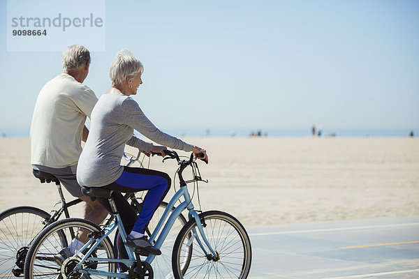 Seniorenpaar beim Fahrradfahren am Strand