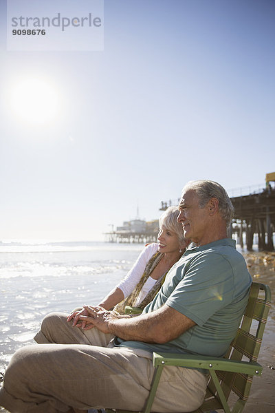 Seniorenpaar entspannt in Liegestühlen am Strand