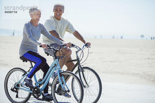 Seniorenpaar mit Fahrrädern an der Strandpromenade