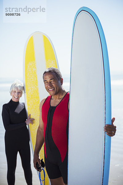 Porträt eines Seniorenpaares mit Surfbrettern