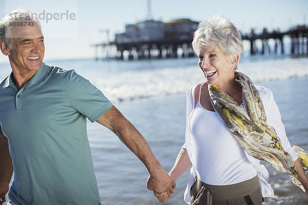 Enthusiastisches Seniorenpaar beim Laufen am Strand