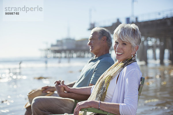 Porträt eines Seniorenpaares in Liegestühlen am Strand