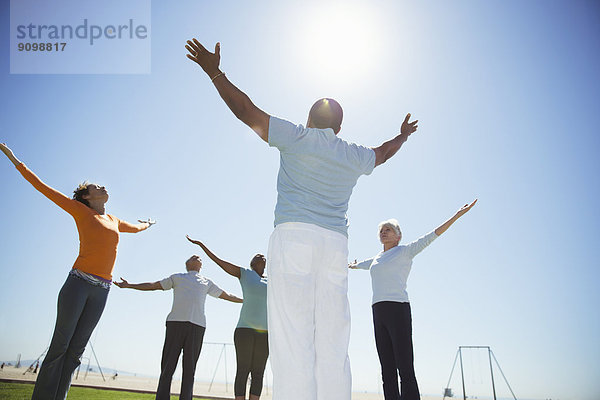Senioren beim Yoga unter sonnigem  blauem Himmel