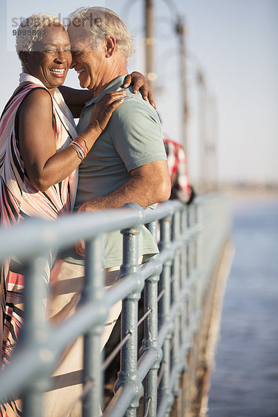Seniorenpaar beim Umarmen am Pier