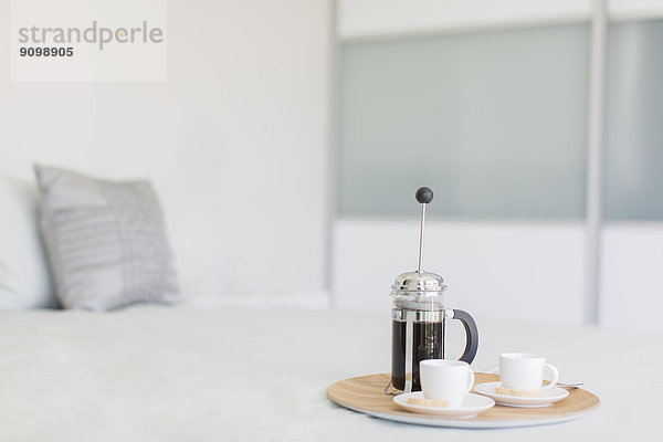 Französischer Presskaffee und Tassen auf Tablett im Schlafzimmer