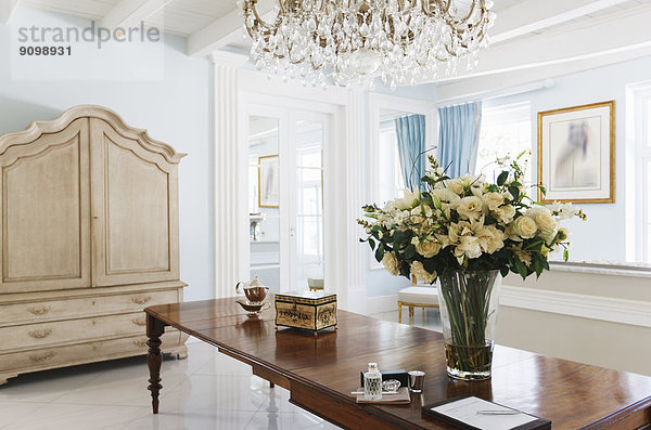 Kronleuchter über Rosenstrauß auf Tisch im luxuriösen Foyer