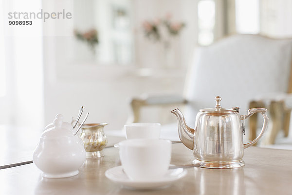 Teetassen und silberne Teekanne auf dem Tisch