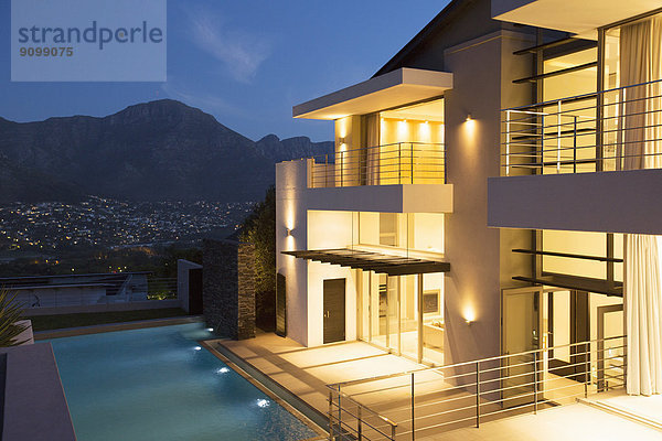 Modernes Haus mit Schwimmbad bei Nacht beleuchtet