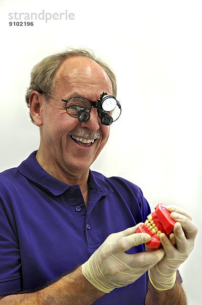 Zahnarzt mit Stirnlampe und Gebiss-Modell