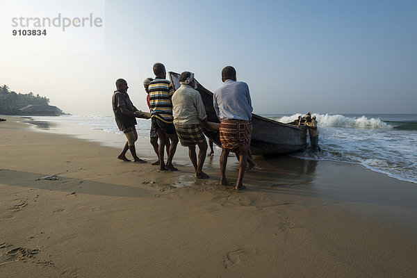 Die Fischer ziehen ein Boot auf den Strand  Varkala  Kerala  Indien