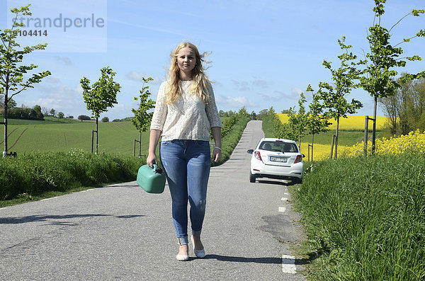 Frau mit einem Benzinkanister in der Hand entfernt sich von ihrem Auto  Schonen  Schweden