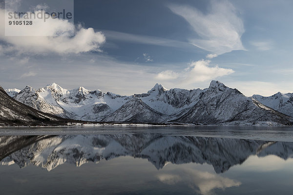 Verschneite Bergkette spiegelt sich im Wasser  Vågan  Lofoten  Norwegen