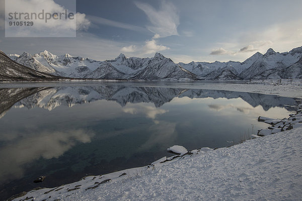 Verschneite Bergkette spiegelt sich im Wasser  Vågan  Lofoten  Norwegen