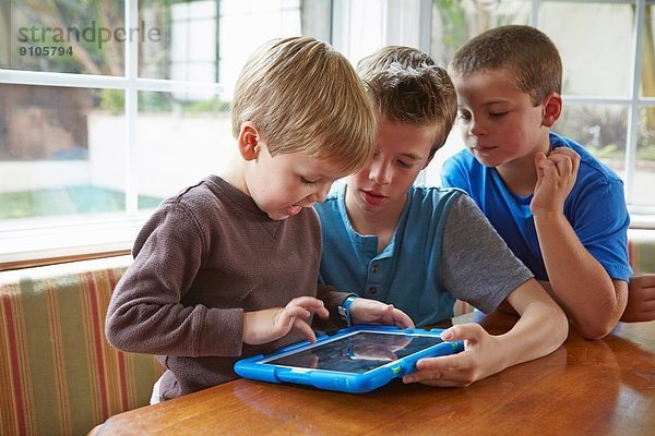 Drei Jungen spielen mit digitalem Tablett