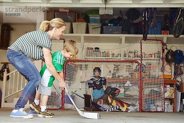 Mutter spielt Hockey in der Garage mit zwei Söhnen