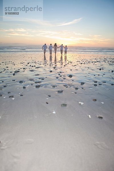 Familie läuft bei Sonnenuntergang Richtung Meer  Kapstadt  Südafrika