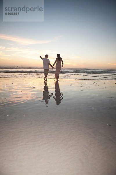 Pärchen hält Hände am Strand bei Sonnenuntergang  Kapstadt  Südafrika