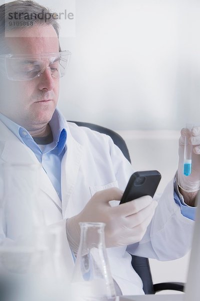 Wissenschaftler mit Smartphone und Reagenzglas