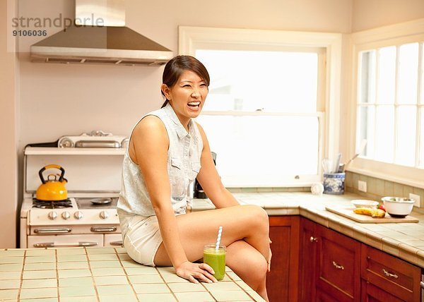 Junge Frau mit grünem Smoothie in der Küche