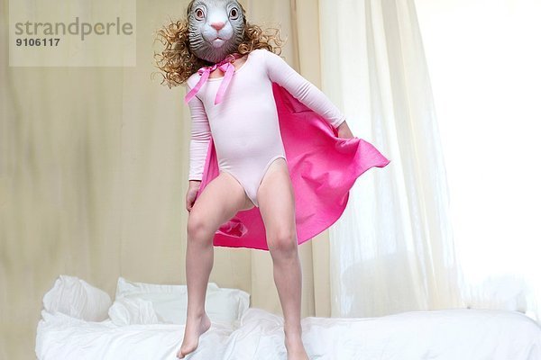 Junges Mädchen verkleidet als Kaninchenprinzessin  die auf dem Bett tanzt.