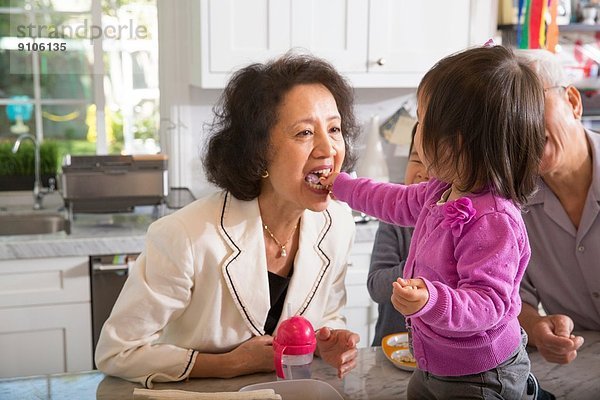 Weibliches Kleinkind füttert Großmutter in der Küche