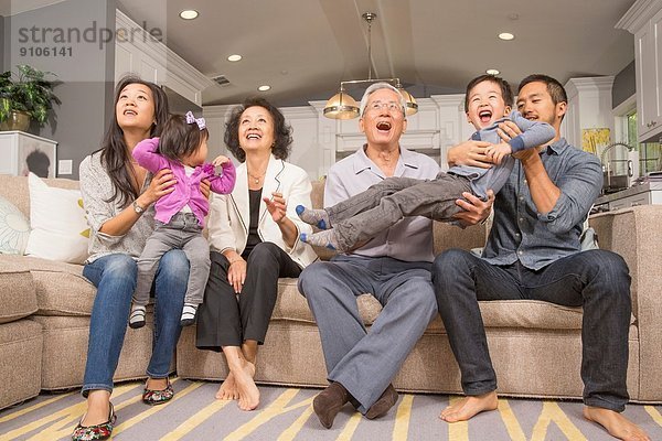 Drei Generationen Familie spielen zusammen auf dem Sofa