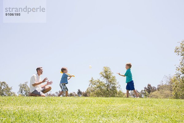 Vater und Söhne spielen Baseball im Park