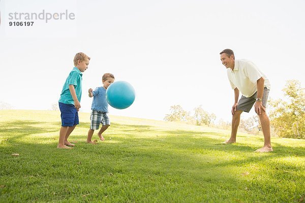 Vater und Söhne beim Ballspielen im Park