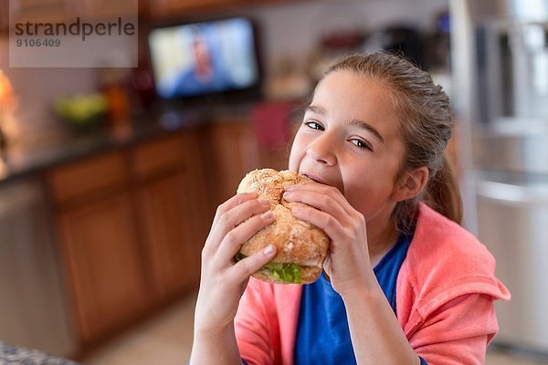 Mädchen in der Küche beißt Sandwich
